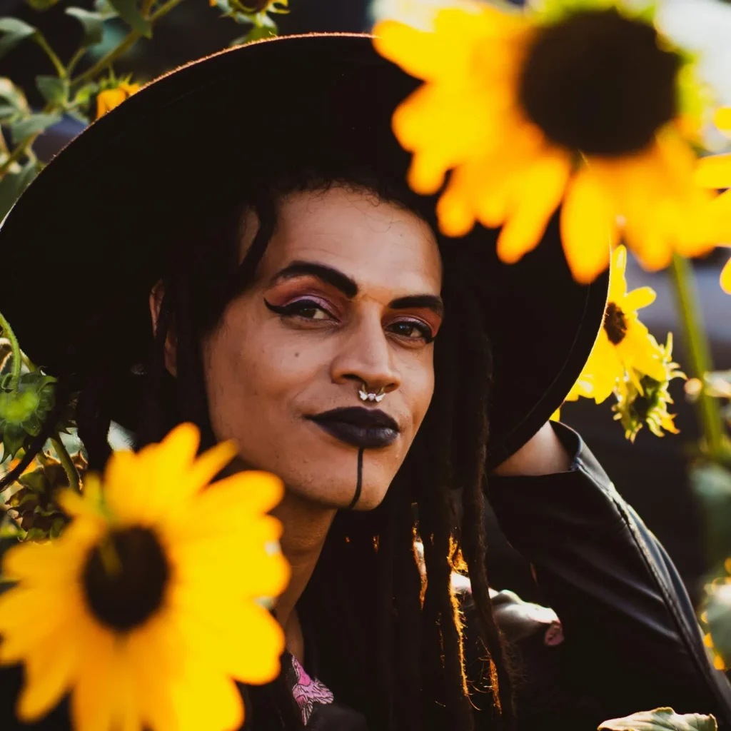 Zaza VanDyke wears a black hat and black lipstick in a field of sunflowers