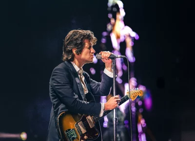 Alex Turner playing guitar and singing at the Delta Center.