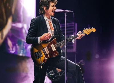 Alex Turner playing guitar and singing at the Delta Center.