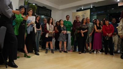 A group of attendees standing and listening to a speaker.