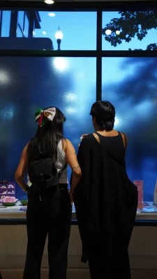 Two people look at a table full of art for sale.