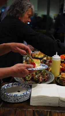 Gallery attendees grabbing food from a table.