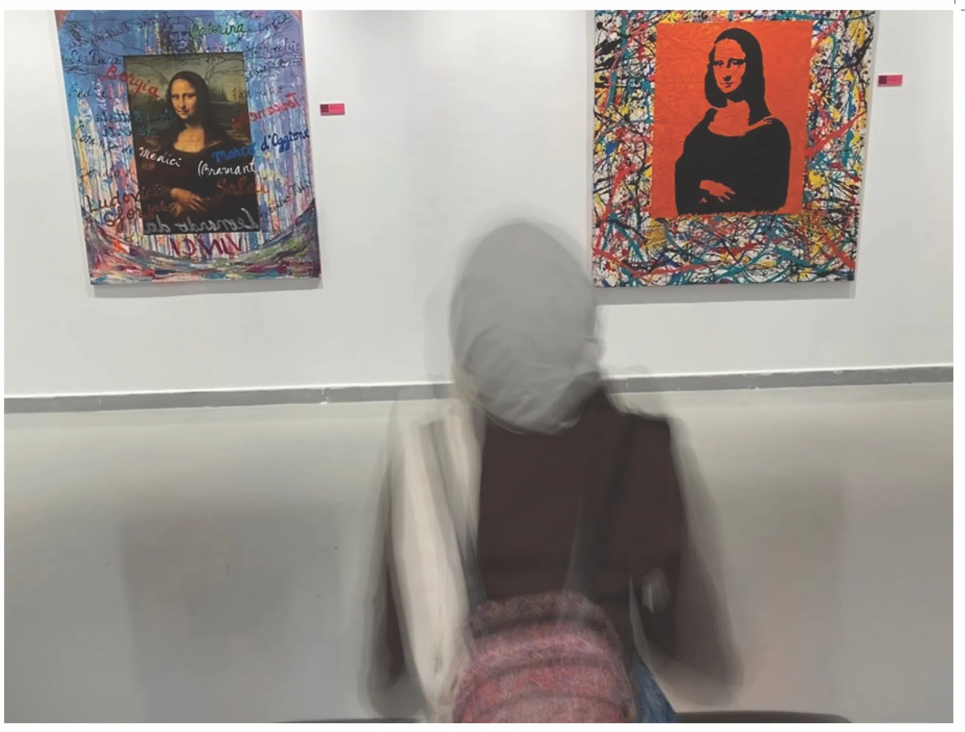Photo of a woman wearing a hijab facing two paintings of the Mona Lisa with bright colors and words altering the well-known image.