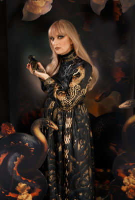 Rebecca Vernon of The Keening stands in a black dress holding a little bird