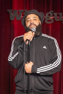 Tanner Nicholson holds a microphone onstage at Wiseguys.