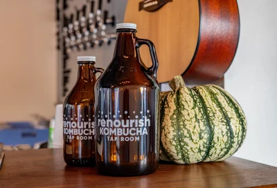 Bottles of kombucha on a table next to a decorative pumpkin.