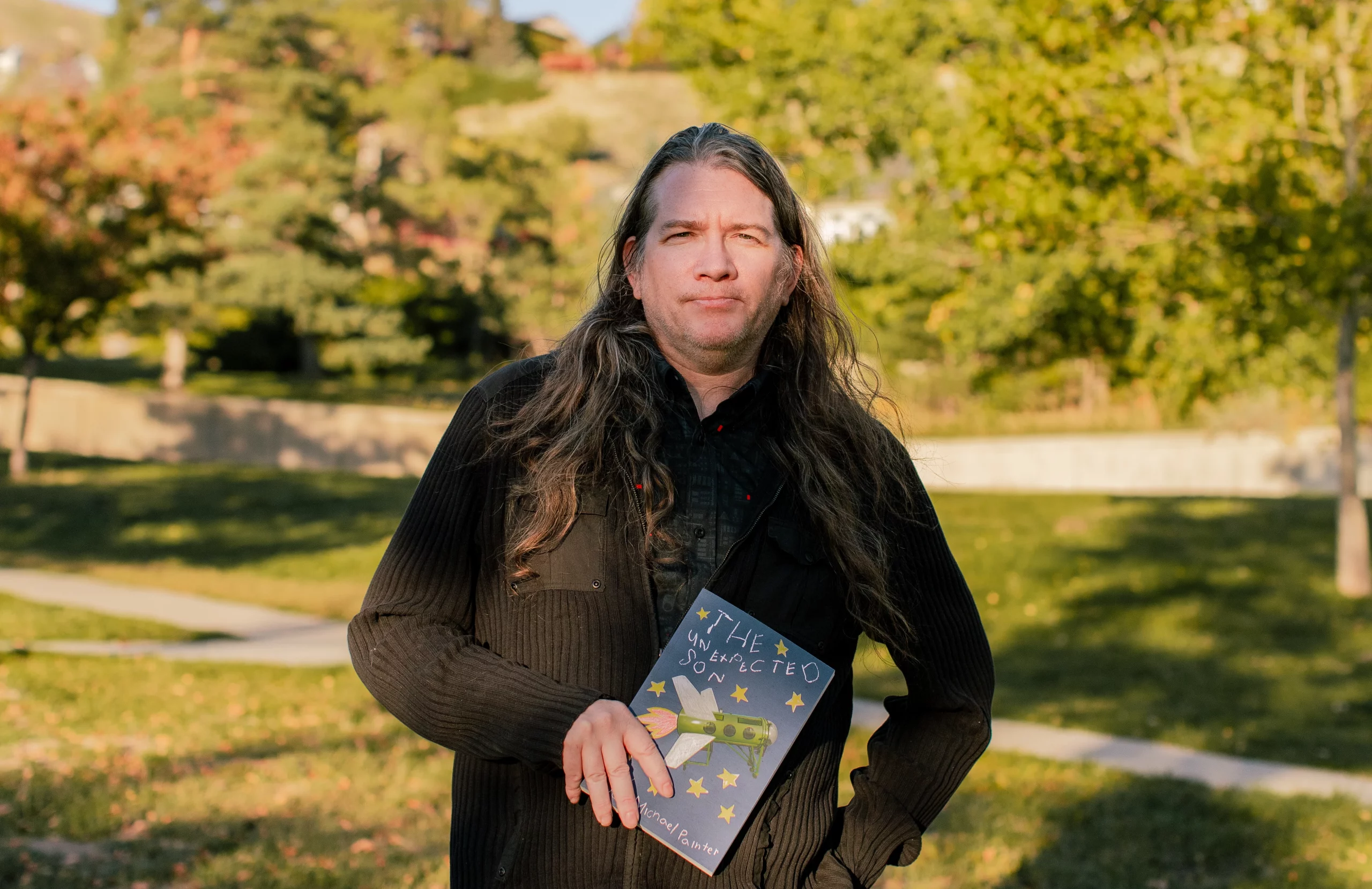 Ryan Michael Painter holding his memoir, The Unexpected Son