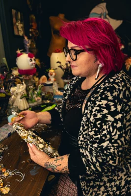 Kaycee Lane, with hot pink hair, assembles a headband.