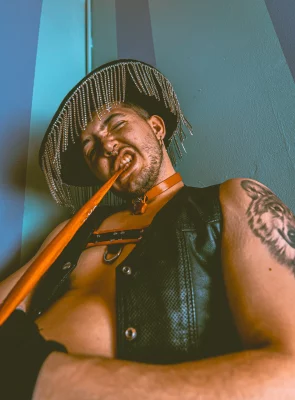 Baby J bites a bandana wearing a tassled cowboy hat.