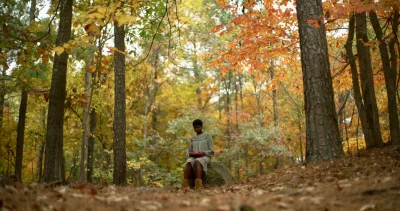 Makayla Cain sits on a rock in the forest.