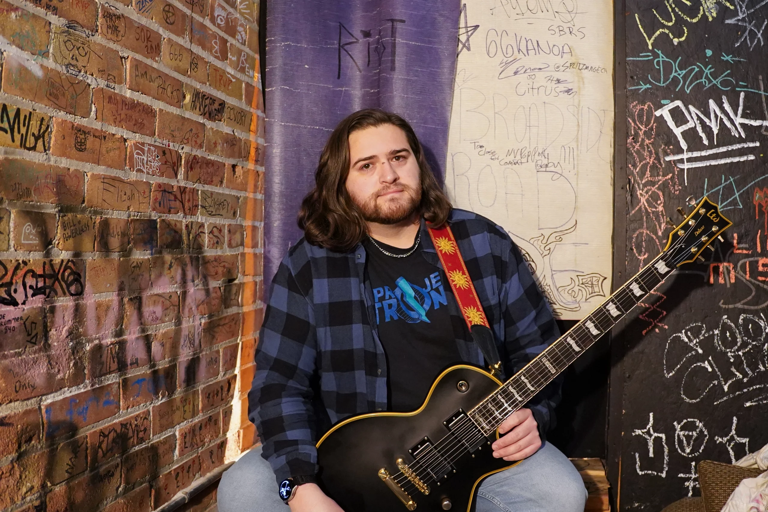 Mike holds a guitar.