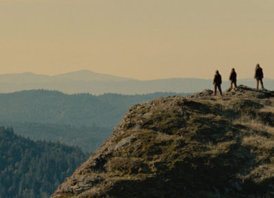 A group of Sasquatches looked over a cliffside to enjoy a sunset.