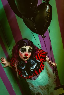 Shortcake holds balloons in front of a striped wall.