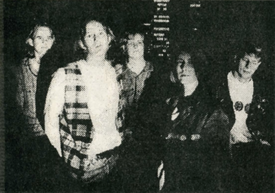 The band, Commonplace, stands in a dimly lit room barely visible.