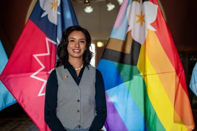 A woman stands in front of a number of pride flags.