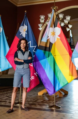 A woman stands in front of pride flags.