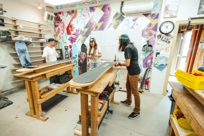 (From L–R) Alister Horn, Sid Garrido and Kate Colgan stand at work benches in their shop.