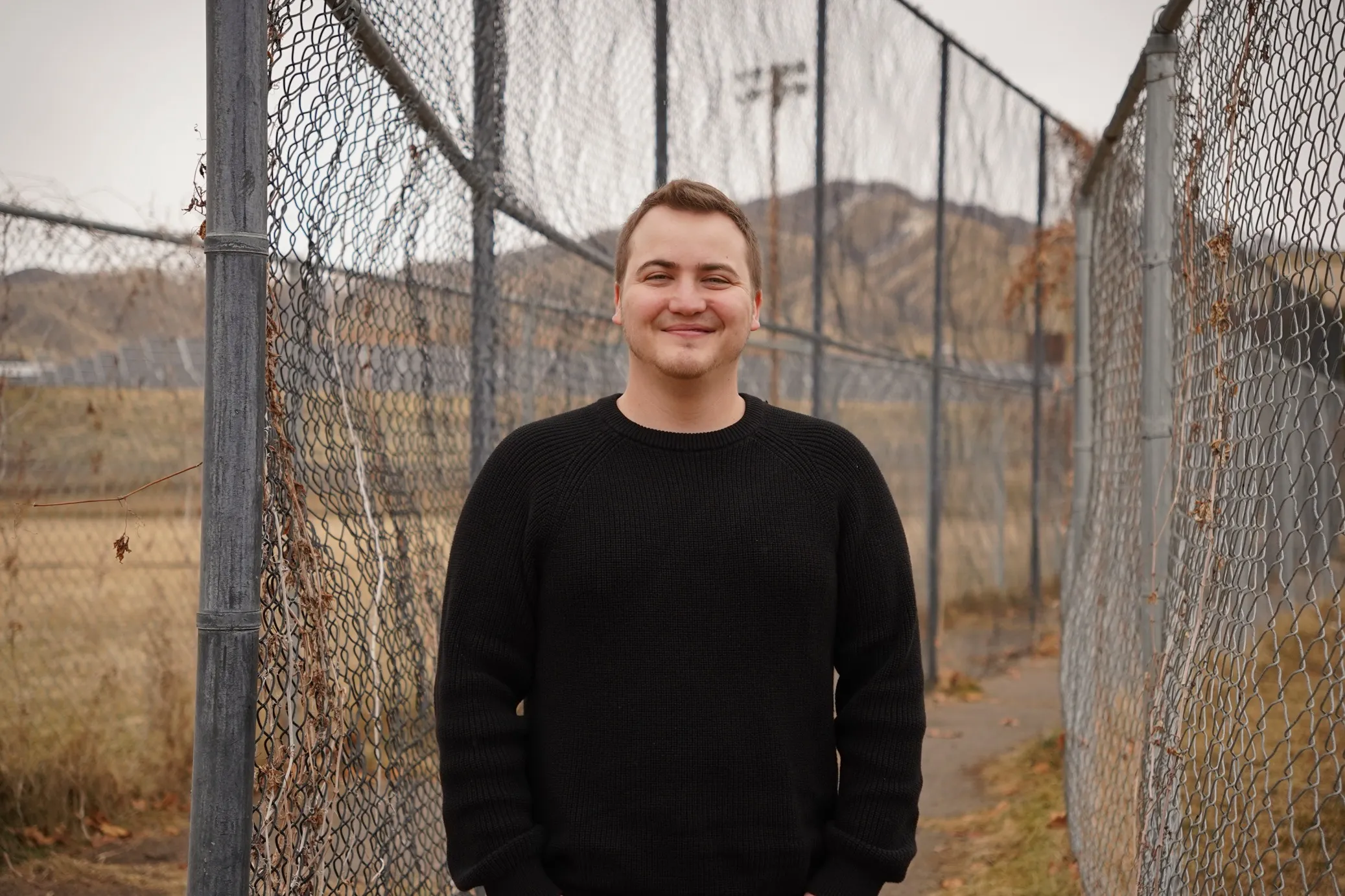 David Sant stands next to a chain link fence.