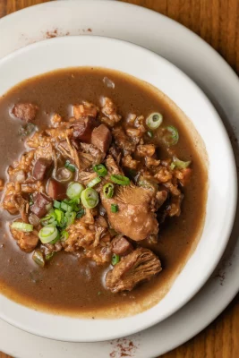 A bowl of gumbo in a white dish.