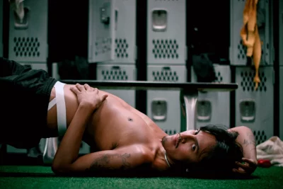 A person poses on the floor of a locker room.