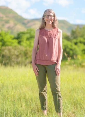 Lisa Thompson posing with a smile in a field of grass with trees in the background.