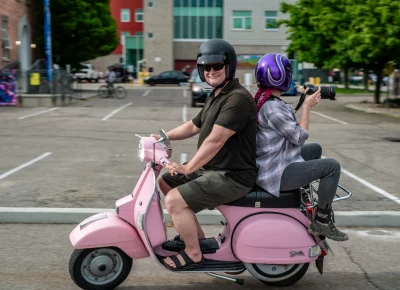 John Barkiple and TaCara DeTevis ride on a scooter to take photos. Photo: Ashley Christenson.