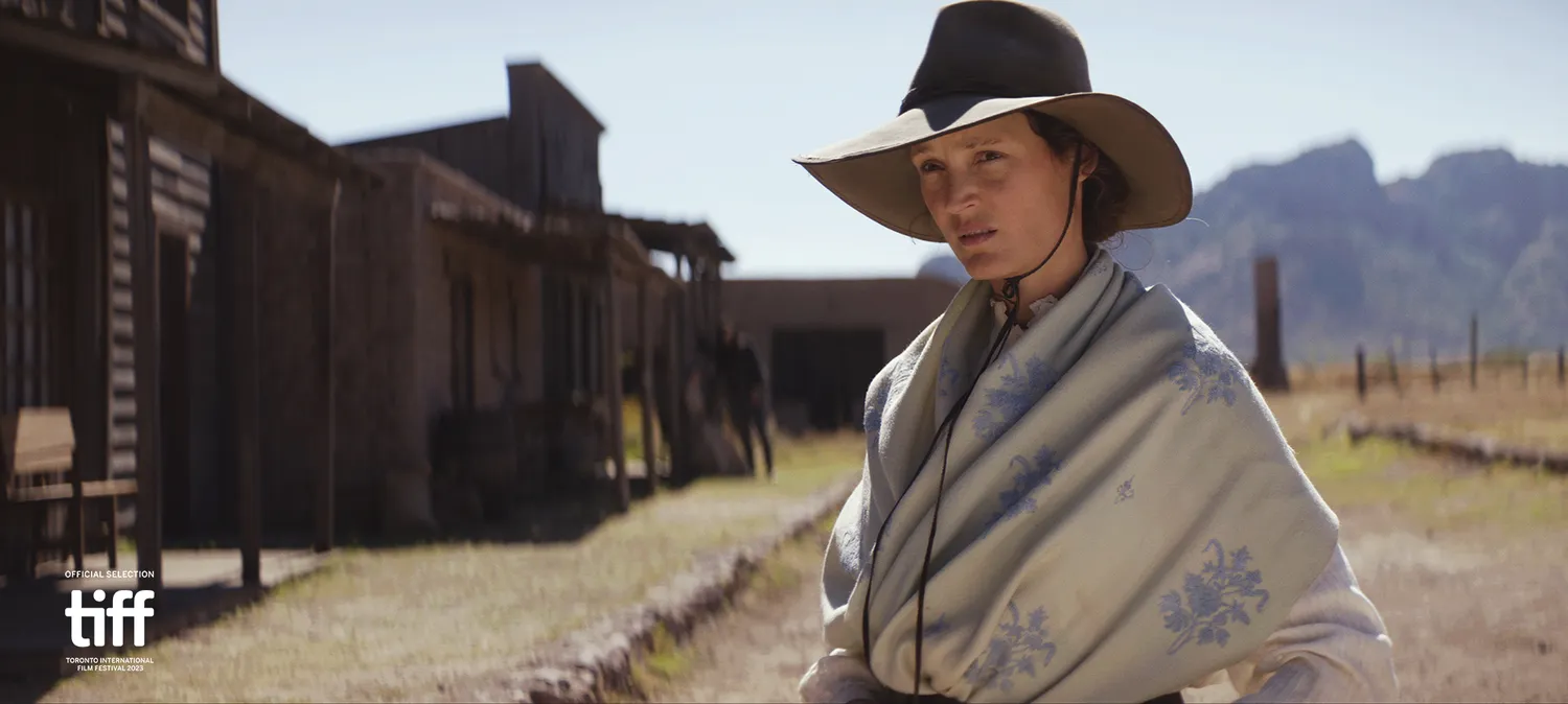 Woman wearing a cowboy hat and poncho looking into the distance.