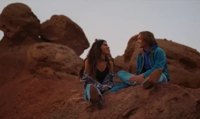 Two people sitting on rocks having a conversation.