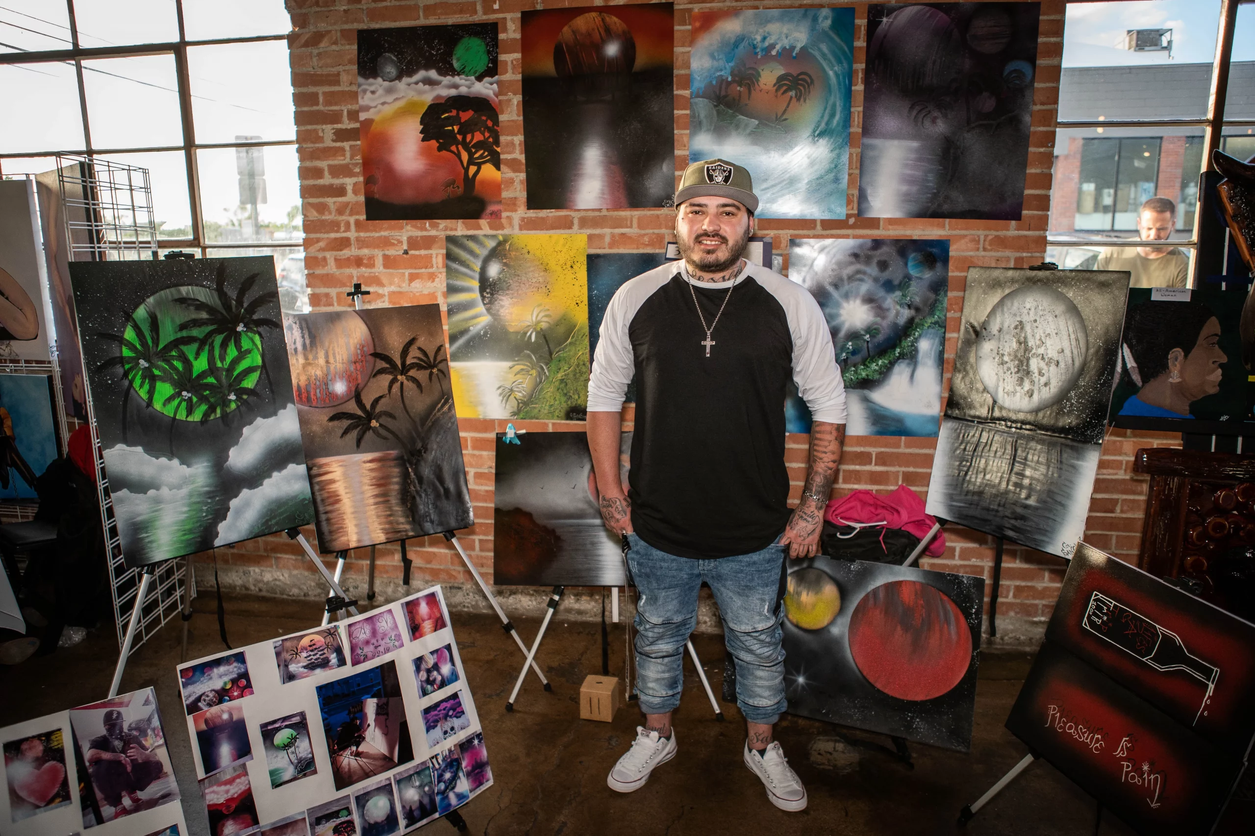 George Sanchez smiles with his display of artwork behind him.