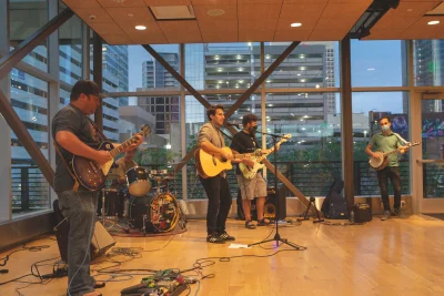 Beard of Bees performs in a room with walls of windows. 