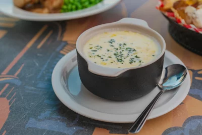 A cup of creamy, yellow soup sits on a table. 