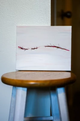 A painting of a scar sits upon a wooden stool. 