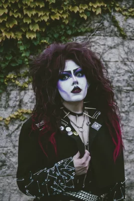 Cherry Poppins stares wide-eyed into the camera in front of an ivy-covered wall.