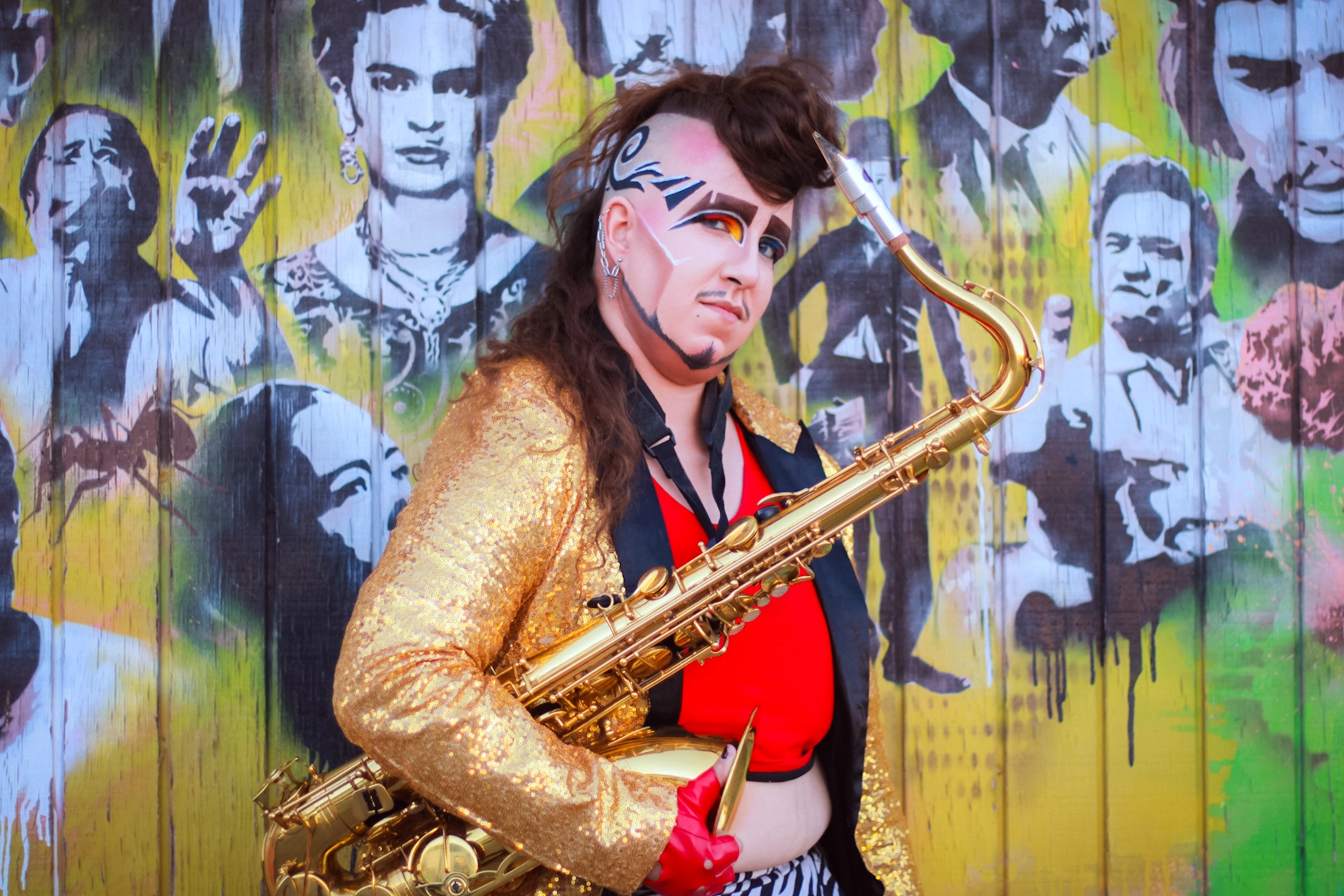 Notta Genda stands in front of a mural with a saxaphone