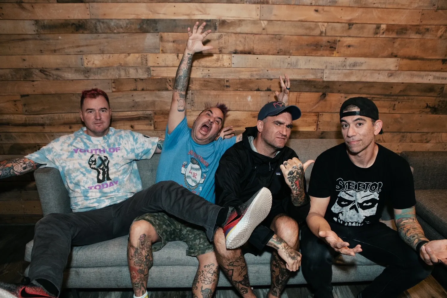 The members of New Found Glory sit on a couch.