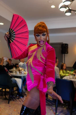 Divina 2.0 strikes a pose holding a fan and wearing an all-pink outfit.