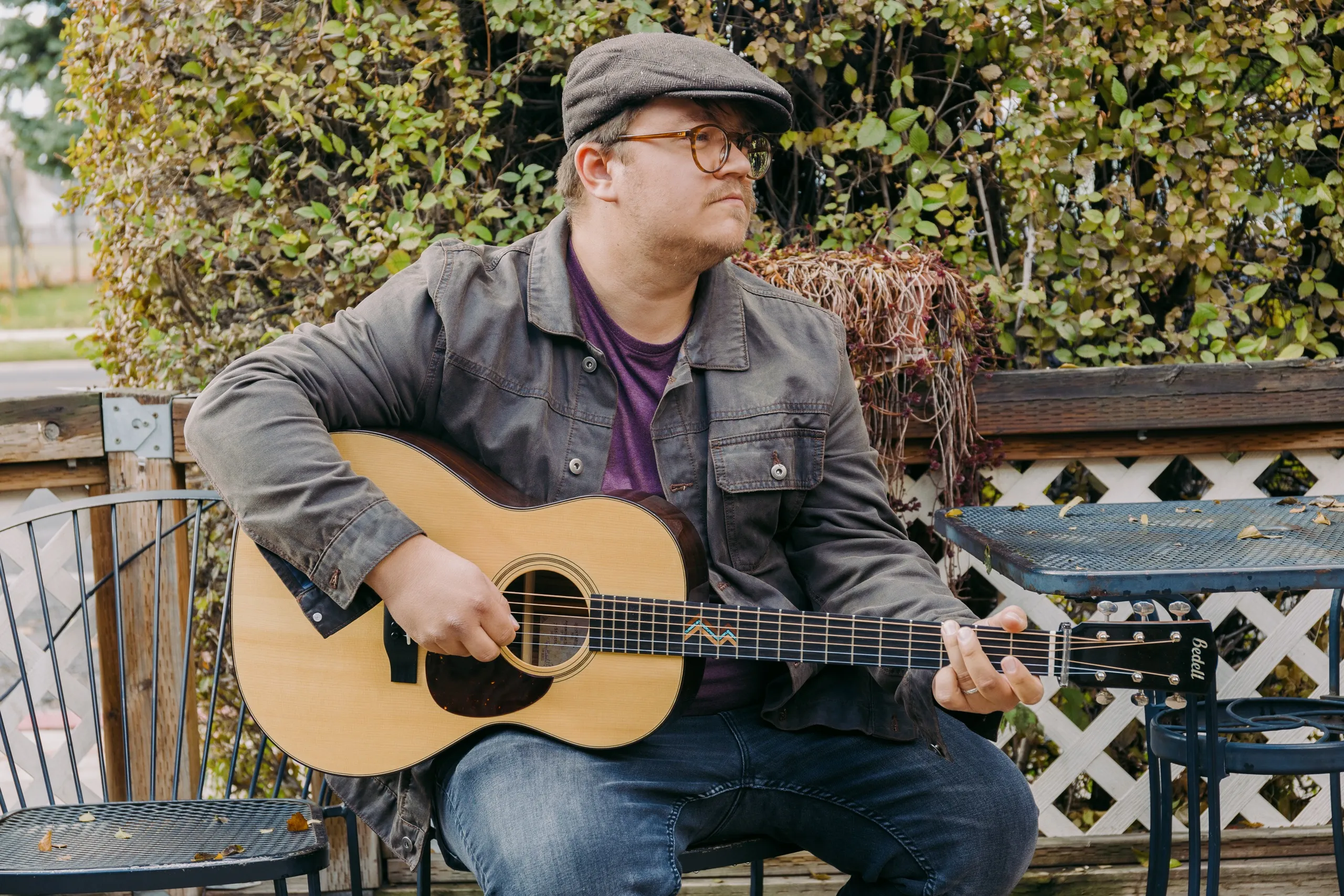 John Elwood Morgan sits on a coffee shop patio with his acoustic guitar.