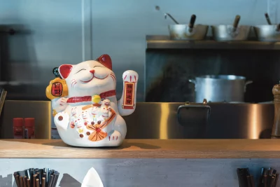 A maneki neko welcomes customers in front of the open kitchen.