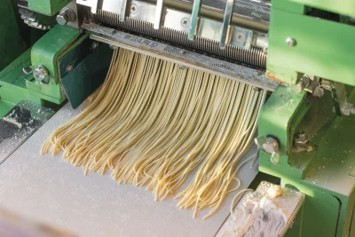 Noodles are pulled and cut through a specific machine.