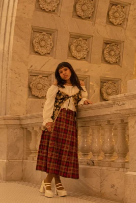 Aura Martinez Sandoval wears a red plaid maxi skirt and a flowy, puffy-sleeved top.