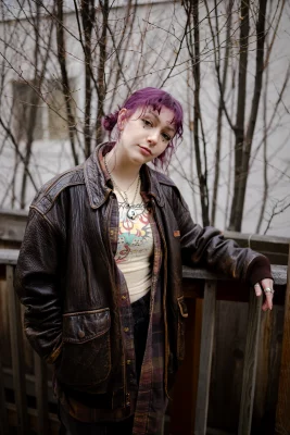 Mariel Croft leaning on a railing in her brown leather trench coat. 