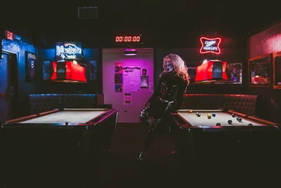 Lorem Ipsum in a neon-lit room, leaning on a pool table.