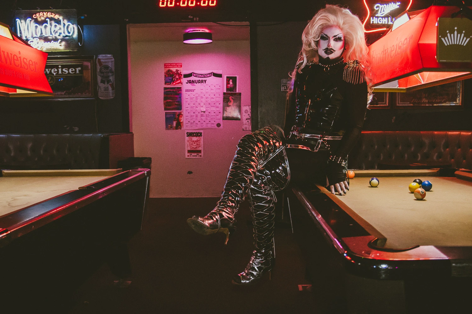 Lorem Ipsum in a neon-lit room, sitting on the edge of a pool table.