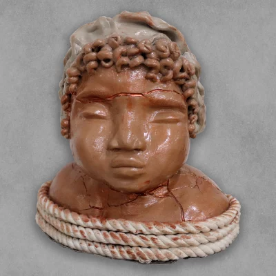 A ceramic sculpture of a cherubic child's head bound in rope.