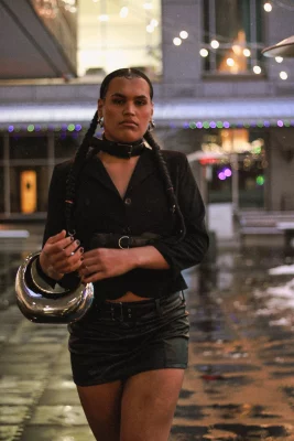 Jaemen Cobb walks toward the camera in a black outfit with a metallic purse.