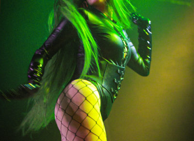 Penny Layne giving high energy and confidence as they turn to look back at the audience.