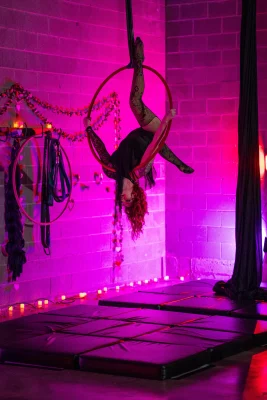 A performer hangs upside down inside a hoop.