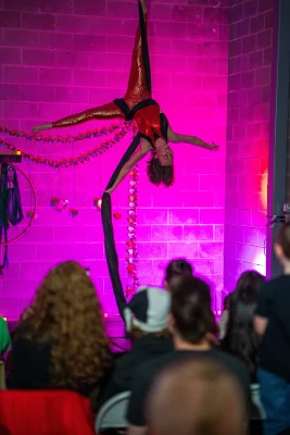 A performer hangs from silks with all limbs outstretched.