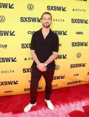 Kyle Hausmann-Stokes stands on a read carpet for the premiere of his film.