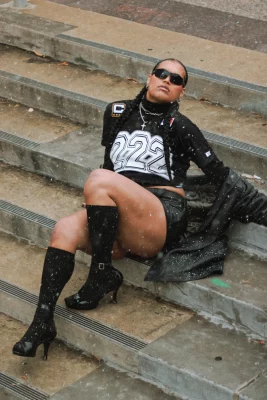 Jaemen Cobb sits on concrete steps in sunglasses and heels.